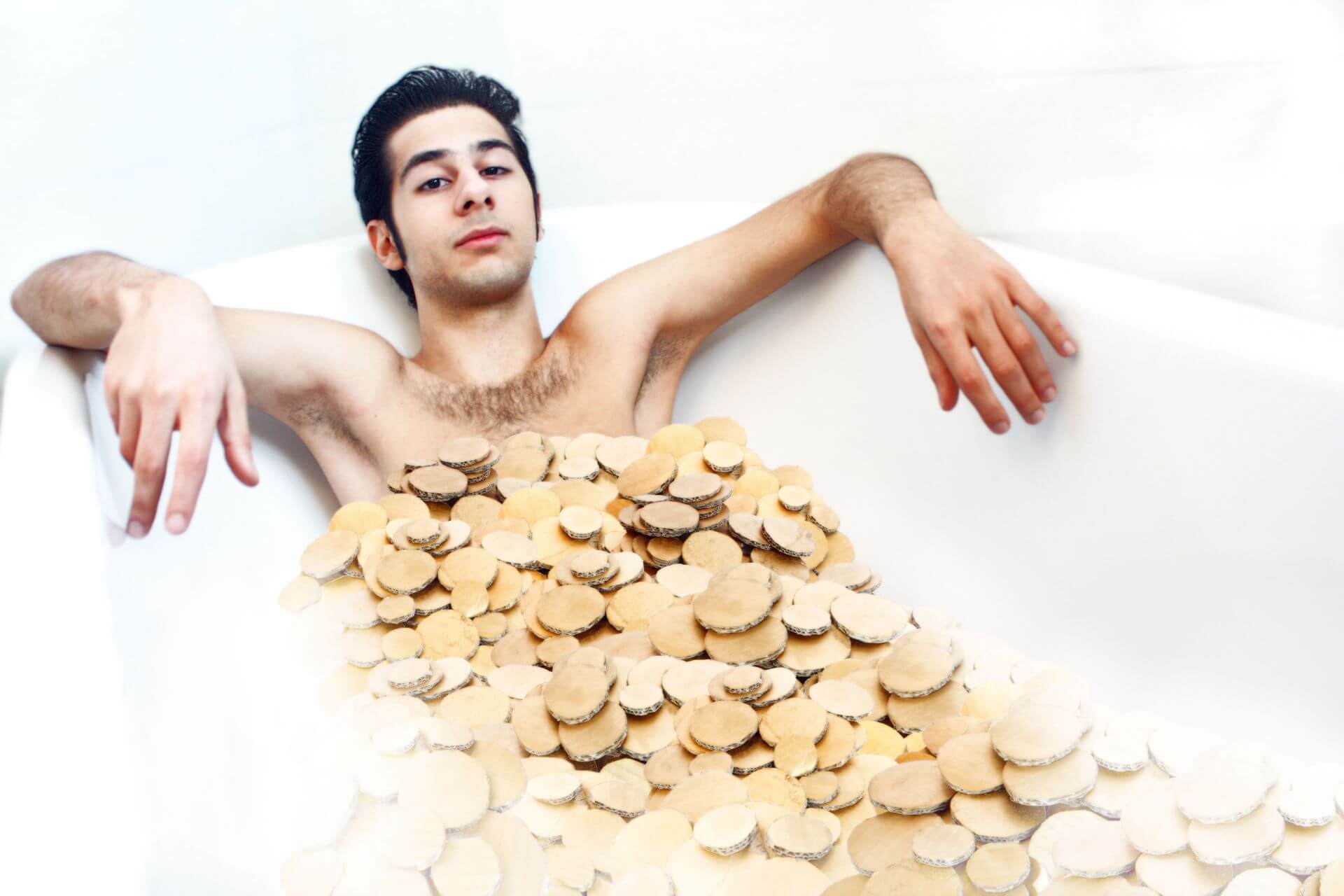 junger Mann in der Badewanne mit falschen Münzen